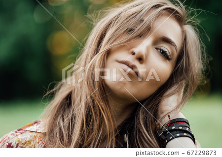 Close up Beautiful young woman wearing bohostyle clothes posing in the rays of the evening sun, sunset. Boho style fashion, female wearing silver jewelry having fun in park outdoors. Close up Beautiful young woman wearing bohostyle clothes posing in the rays of the evening sun, sunset. Boho style fashion, female wearing silver jewelry having fun in park outdoors. 67229873