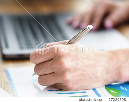 Man at home makes notes in report near laptop Man at home makes notes in report near laptop 67229898