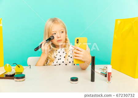 Happy girl at home speaking in front of camera for vlog. Young beauty blogger recording video tutorial for Internet. 67230732