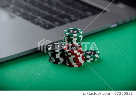 Casino chips and laptop on green background. Casino online concept Casino chips and laptop on green background. Casino online concept 67230831