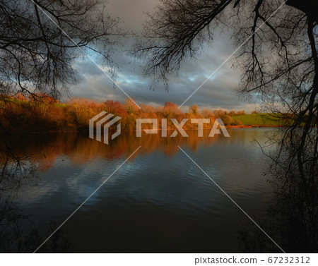 Picturesque lake shore in sunset tones Picturesque lake shore in sunset tones 67232312