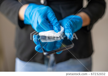 Woman's hand in blue gloves cleaning smartphone 67232832