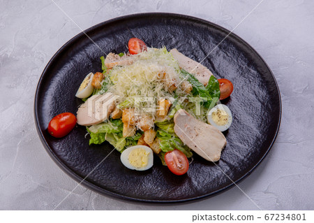 Caesar salad with chicken breast on a dark plate. Home-made chicken fillet, cherry tomatoes 67234801