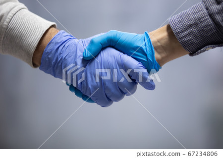 Handshaking with blue protective gloves Handshaking with blue protective gloves 67234806