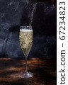 Barman pours champagne into a glass. Bubbles of champagne in a glass on a dark background. European 67234823
