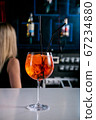 Aperol Cocktail. Fresh cocktail in a glass with ice on a white bar counter against a dark background 67234880