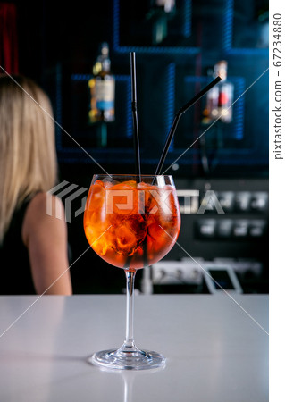 Aperol Cocktail. Fresh cocktail in a glass with ice on a white bar counter against a dark background Aperol Cocktail. Fresh cocktail in a glass with ice on a white bar counter against a dark background 67234880