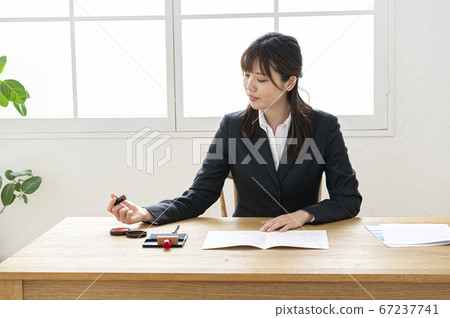 Woman in business suit imprinting documents at desk 67237741