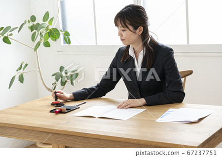 Woman in business suit imprinting documents at desk 67237751