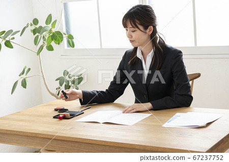 Woman in business suit imprinting documents at desk Woman in business suit imprinting documents at desk 67237752