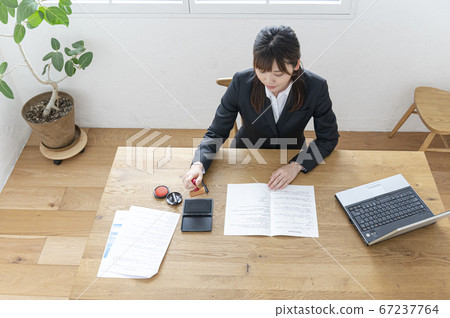 Woman in business suit imprinting documents at desk 67237764