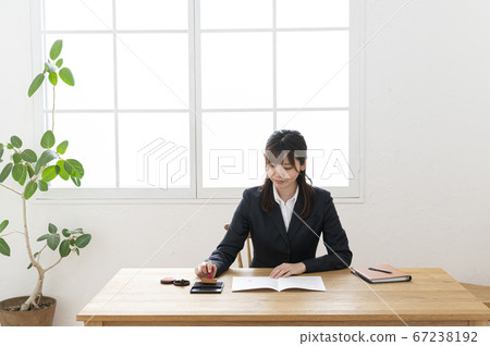 Woman in business suit imprinting documents at desk 67238192