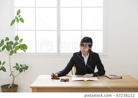 Woman in business suit imprinting documents at desk Woman in business suit imprinting documents at desk 67238212