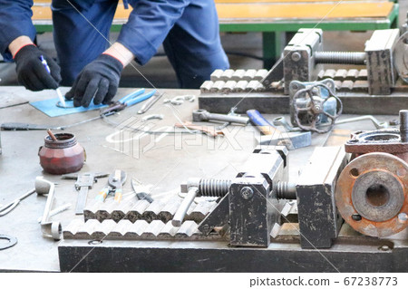 The worker works on a table with a metalwork tool The worker works on a table with a metalwork tool 67238773