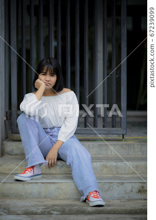 seriously face of asian teenager sitting at road seriously face of asian teenager sitting at road 67239099
