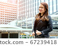 Beautiful young asian business woman standing in front of office building in business area. 67239418