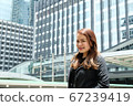 Beautiful young asian business woman standing in front of office building in business area. 67239419