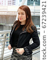 Beautiful young asian business woman standing in front of office building in business area. 67239421