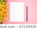 Top view or flat lay of open notebook paper, yellow orchid flowers and pencil on pink background. 67239426