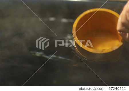 Scoop hot spring water in a bath tub 67240311