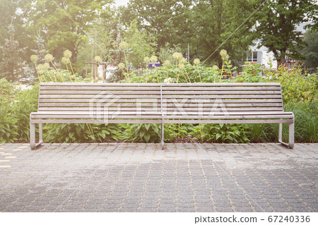 Wooden benches with metal construction in an urban environment for relaxation at greenery 67240336