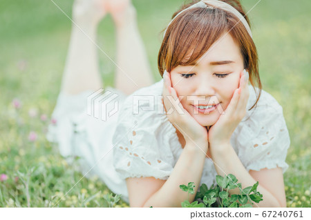 一位身穿白色連衣裙的亞洲女性，臉頰貼在大自然中 67240761