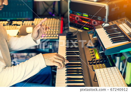 male musician, producer, composer playing electric piano in home studio 67240912
