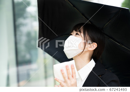 Business woman wearing a mask and holding a parasol 67241493