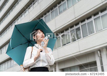 指向一個塑料瓶她的面孔和拿著遮陽傘的女商人 67241495