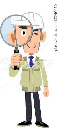 A man in work clothes wearing a helmet looking through a magnifying glass 67246410