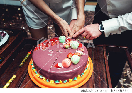 wedding ceremony. the bride and groom make their first case together, cutting the violet wedding cake 67246784