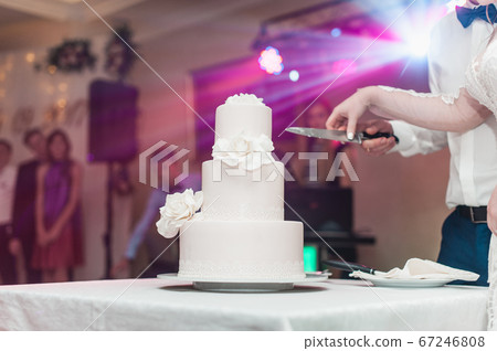 wedding ceremony. the bride and groom make their first case together, cut the white wedding cake 67246808