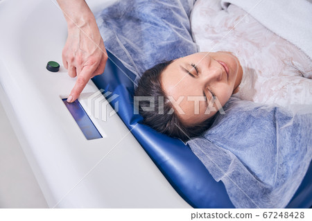 Beautician switching on the floating device in spa salon Beautician switching on the floating device in spa salon 67248428