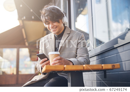Cheerful young man using cellphone in outdoor cafe Cheerful young man using cellphone in outdoor cafe 67249174