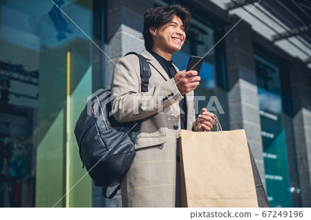 Joyful young man using smartphone on the street Joyful young man using smartphone on the street 67249196