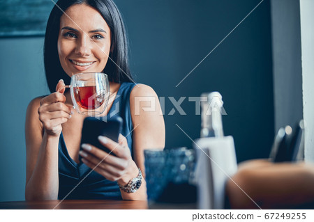 Woman sitting at the table and holding cup of tea 67249255