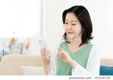 在客廳裡操作智能手機的中年女人 在客廳裡操作智能手機的中年女人 67249726
