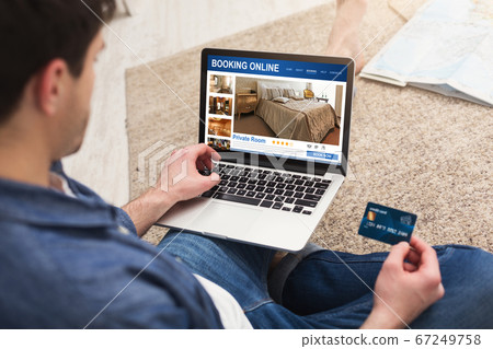 Man holding laptop with hotel booking website and credit card Man holding laptop with hotel booking website and credit card 67249758