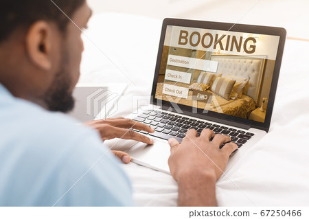 African american man browsing hotel booking website on laptop African american man browsing hotel booking website on laptop 67250466
