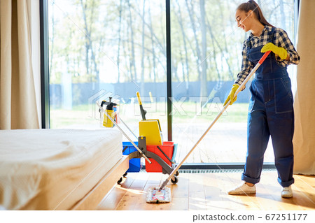 Beautiful young woman cleaner cleaning floor at home using mop Beautiful young woman cleaner cleaning floor at home using mop 67251177
