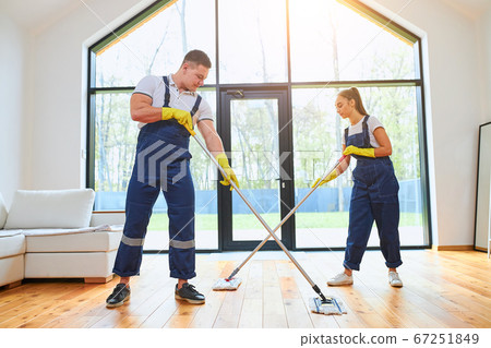 Caucasian janitors in uniform mopping floor together Caucasian janitors in uniform mopping floor together 67251849