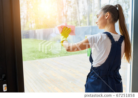 Rear view on young cleaner lady washing glass of window Rear view on young cleaner lady washing glass of window 67251858