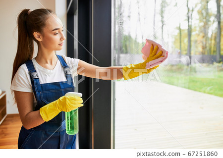 Young woman cleaning big window with sprayer and sponge 67251860