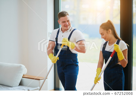 Janitors in special clothes washing floor in new house 67252008