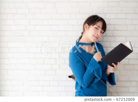 Beautiful asian woman smiling standing thinking and writing notebook. Beautiful asian woman smiling standing thinking and writing notebook. 67252009