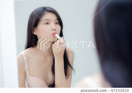 Beautiful young asian woman applying lipstick pink with style bright and shiny on mouth. 67252010