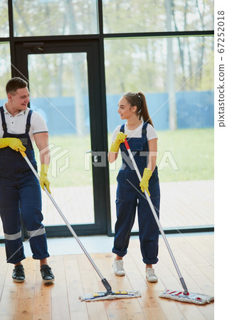 Two janitors with mop cleaning new house Two janitors with mop cleaning new house 67252018