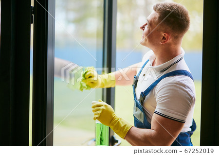 Handyman cleaning panoramic window wearing yellow gloves Handyman cleaning panoramic window wearing yellow gloves 67252019