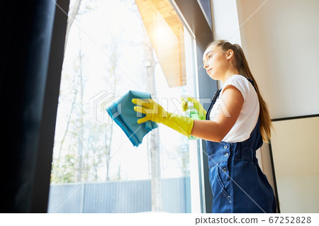 Side view on young cleaner in uniform cleaning Side view on young cleaner in uniform cleaning 67252828