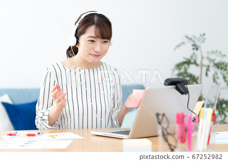 Telework Young woman wearing white headphones at home for a web conference 67252982